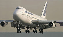 Aircraft front view with extended flaps and landing gear.