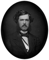 Black-and-white photograph of a young man with a mustache