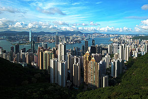 panorama: looking down on a city of skyscrapers, land mass in the distance separated by a body of water.