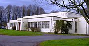 White concrete single story building, with vegetation around